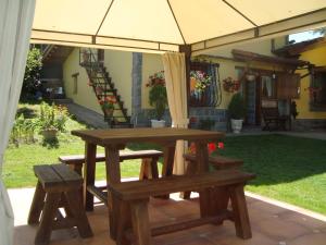 una mesa de picnic y un banco bajo una sombrilla en Apartamentos La Huerta de la Torre, en Cangas de Onís