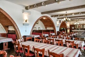 a dining room with tables and chairs and arches at Hotel R&oacute;zsa Cs&aacute;rda in Hegyeshalom
