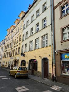 um carro amarelo estacionado em frente a um edifício em Apartament De Luxe Emily em Jelenia Góra