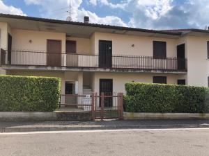 une maison blanche avec un balcon et des buissons dans l'établissement Appartamento con Piscina a Lazise, à Lazise