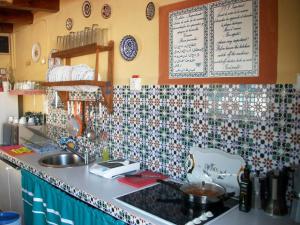 a kitchen with a counter with a sink and a menu on the wall at Pensión Moni Albayzin in Granada