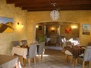 a restaurant with tables and chairs and a clock on the wall at Le H de SERNHAC in Sernhac