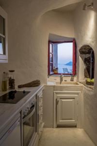 a white kitchen with a sink and a window at The sculptor's house by Cycladica in Oia