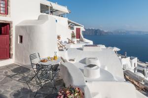 a balcony with a table and chairs and the ocean at The sculptor's house by Cycladica in Oia