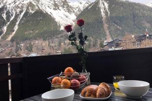 a table with a bowl of fruit and a vase with roses at Chamonix sud -Le Grepon in Chamonix-Mont-Blanc