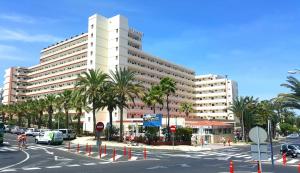 un grande edificio bianco con palme di fronte a una strada di Eldorado Casa Gi a Playa de las Americas