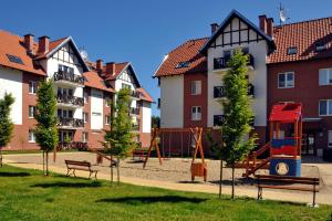 a park with a playground in front of buildings at Apartament Ohar in Sztutowo