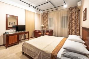 a bedroom with a bed and a desk and a television at The Regent Club Hotel in Niš