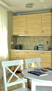 uma cozinha com armários de madeira e uma mesa e cadeiras em Apartament Ohar em Sztutowo