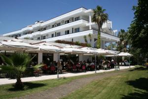 un grande edificio bianco con tavoli e ombrelloni di Hotel Club Clorinda nuova gestione 2024 a Paestum