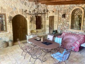 a table and chairs in a room with a stone wall at Finca Ses Fontanelles in Andratx