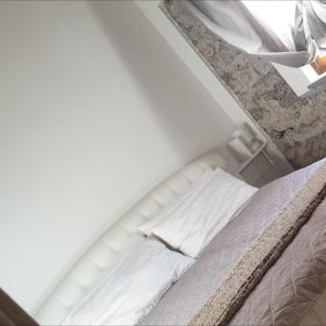 1 cama con sábanas blancas y almohadas en una habitación en La Locanda dei Cavalieri, en Mormanno