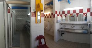 un bagno pubblico con lavandino e sedia rossa di Campingplatz mit Restaurant & Sportarena Leukerbad a Leukerbad