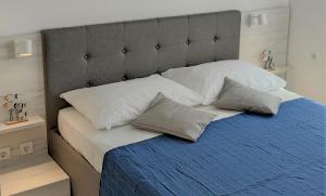 a bed with white pillows and a gray headboard at Apartments Riba in Vis