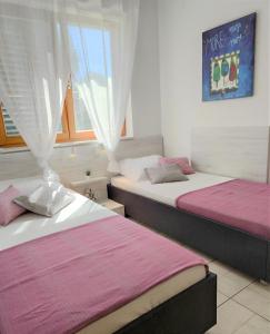 two beds sitting in a room with a window at Apartments Riba in Vis