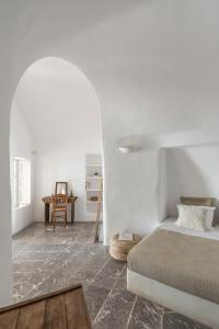 une chambre blanche avec un lit et une table dans l'établissement Parathira cave houses oia by cycladica, à Oia
