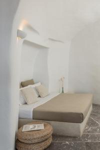 une chambre blanche avec un lit et une table dans l'établissement Parathira cave houses oia by cycladica, à Oia