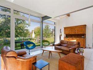 sala de estar con muebles de cuero y ventanas grandes. en Sun kissed Villa in Kobbegem with Private Garden 