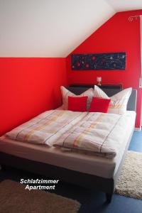 Un dormitorio con una pared de acento rojo y una cama en Haus Sonneneck, en Bad Bocklet