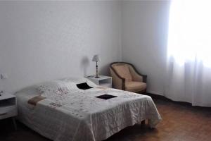 a white bedroom with a bed and a chair at Spacieux appartement proche centre et piscine in Condom