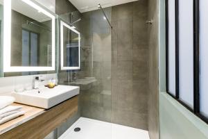 La salle de bains est pourvue d'un lavabo et d'une douche. dans l'établissement Grand Hôtel Clichy Paris, à Clichy