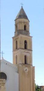 Una torre alta con un reloj en un edificio. en Cinghiale Bianco, en Cagliari