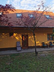 a house with a tree and a table and chairs at Váralja Vendégház Tata in Tata