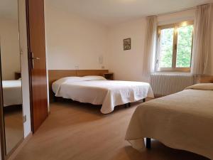 1 dormitorio con 2 camas y ventana en Albergo Miralaghi en Padergnone