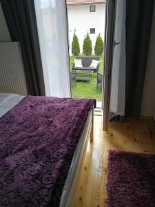 a bedroom with a purple bed and a sliding glass door at Apartman Ena in Nova Varoš