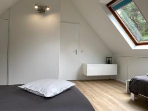 een witte slaapkamer met een bed en een raam bij Vakantiehuisje Time Out in Zelhem