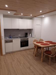 eine Küche mit weißen Schränken und einem Tisch mit Stühlen in der Unterkunft Unterhohnenhof in Triberg
