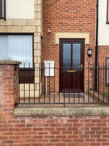 a black door on a brick building with a fence at City Bridge Townhouse 4 in Newcastle upon Tyne