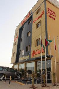 un edificio con dos banderas delante en رانا الخليجية - rana alkhaleejiah, en Riyadh Al Khabra
