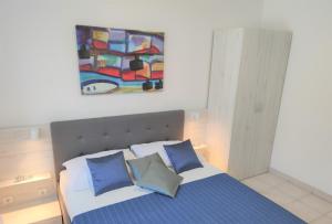 a bedroom with a bed with blue pillows and a painting at Apartments Riba in Vis