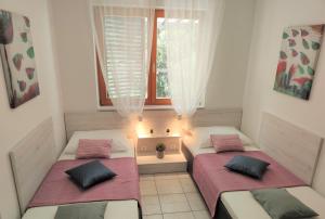 two beds in a small room with a window at Apartments Riba in Vis