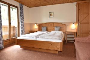 Un dormitorio con una gran cama de madera con sábanas blancas. en Frühstückspension Oberweissburg en Sankt Michael im Lungau