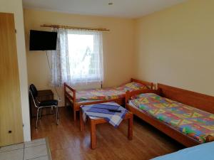 a room with two beds and a table and a television at U Anny i Piotra in Mielenko