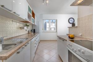 een keuken met witte kasten en een wastafel bij Apartment IN in Rijeka