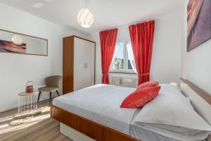 Un dormitorio con una cama con almohadas rojas y una ventana en Apartment IN en Rijeka