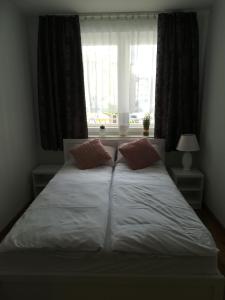 a bed with two pillows in front of a window at APARTAMENT RELAX in Ełk