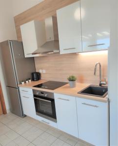 a kitchen with white cabinets and a sink and a refrigerator at Apartments Riba in Vis