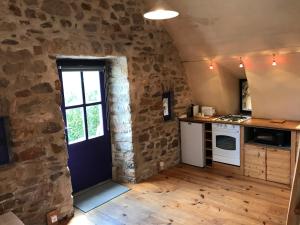 uma cozinha com uma porta e uma parede de pedra em Le gite du Larzac à Brunas em Creissels