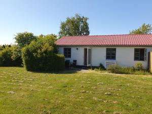 een wit huis met een rood dak en een tuin bij Feriestedet Skovly in Klemensker