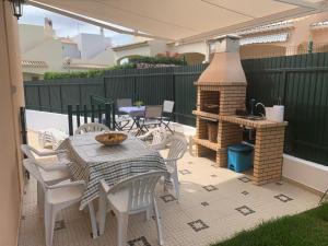 a patio with a table and chairs and a grill at Casa das Roseiras in Ferragudo