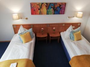 two beds in a room with two tables at Moosburger Hof in Moosburg