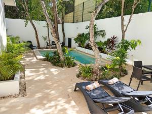 a patio with chairs and a swimming pool with trees at Mi Tulum in Tulum