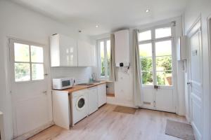 a kitchen with white cabinets and a washer and dryer at Villers-sur-Mer in Villers-sur-Mer