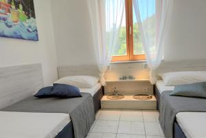 two beds in a room with a window and a sink at Apartments Riba in Vis