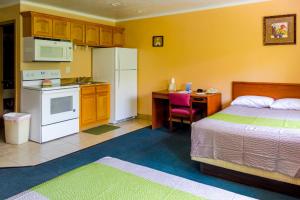 a bedroom with a bed and a kitchen with a white refrigerator at Red River Inn Silt - Rifle in Silt