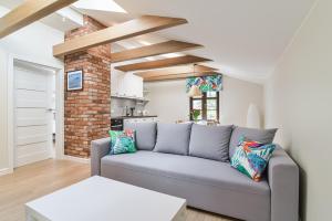 a living room with a gray couch and a brick wall at Villa Allegra Apartments Gdynia Orłowo in Gdynia
